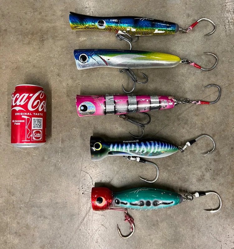 Poppers for GTs from top to bottom - Heru Skipjack, Jackfin Kronos, Blaze Saththa, Nomad Chug Norris, Heru Cubera      Note: These are big lures; that is a standard size soda can.